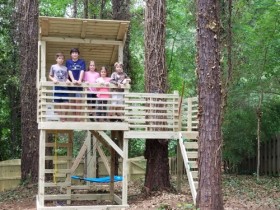 Gorgeous backyard playground with slant roof and horizontal rails.