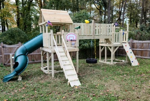 Beautiful custom wooden playset in a green backyard